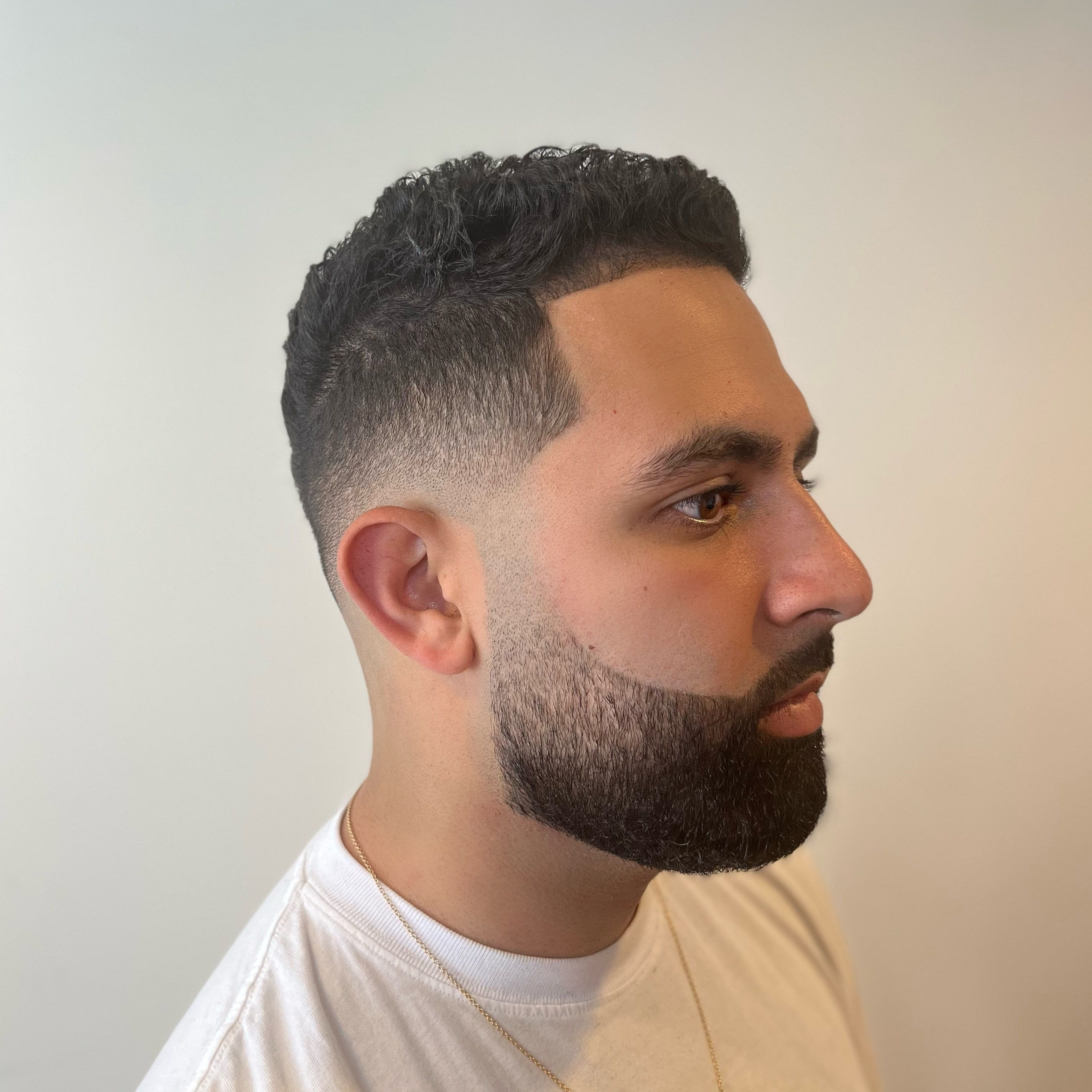 Edgy man with voluminous pompadour haircut by andis clippers on green background.