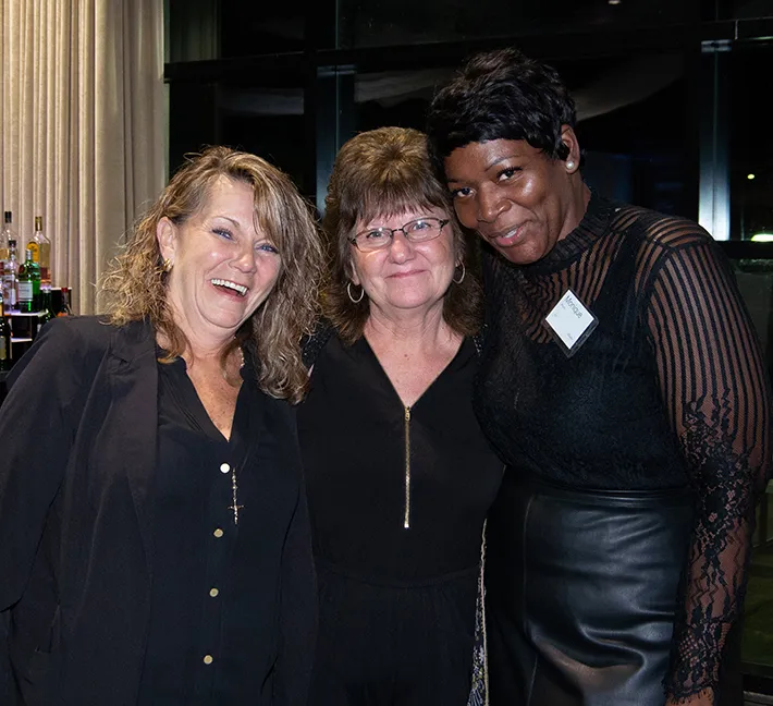 3 female Andis employees arm in arm posing for camera