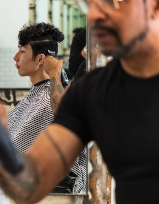 Large image of boy with black hair getting hair cut with Supra cordless clipper